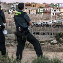 Dos agentes de la Guardia Civil vigilan la frontera de Melilla ante el intento de un grupo de personas de saltarla. AFP
