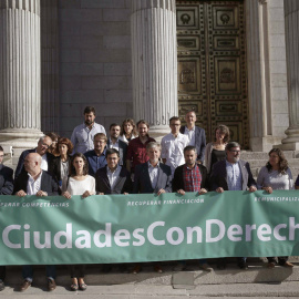 Miembros de Unidos Podemos y representantes de los llamados ayuntamientos "del cambio" posan  a las puertas del Congreso de los Diputados tras presentar una proposición para derogar la ley de Racionalización y Sostenibilidad de la Administr