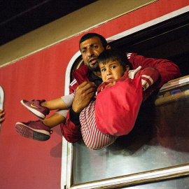 Un hombre sostiene a un niño en un tren rumbo a Serbia desde la frontera entre Macedonia y Grecia. Macedonia es un país clave en la ruta de migración de los Balcanes hacia la Unión Europea.- ROBERT ATANASOVSKI (AFP)