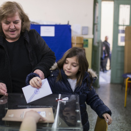 Una mujer deposita su voto con su hija en un colegio electoral de Atenas. REUTERS/Marko Djurica