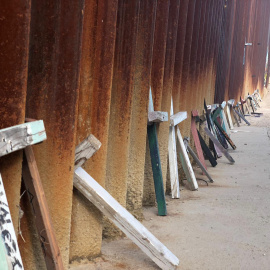 Apoyadas sobre el muro fronterizo en Nogales (México) hay decenas de cruces de madera en honor a los migrantes que perecieron tratando de alcanzar EE.UU. con vida. / Aitana Vargas