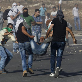Manifestantes palestinos cargan con un compañero herido por disparos israelíes en una manifestación en el checkpoint de Howara, cerca de la ciudad de Nablus, Cisjordania.- EFE/EPA/ALAA BADARNEH