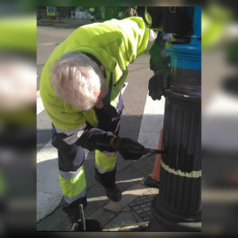 Imagen de un trabajador pintando de negro la bandera arcoíris de un semáforo de Granada.