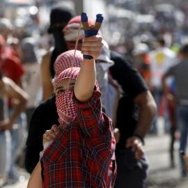Una chica palestina utiliza un tirachinas para lanzar piedras a los soldados israelíes durante los enfrentamientos en la ciudad cisjordana de Belén, 14 de octubre de 2015. REUTERS / Mussa Qawasma