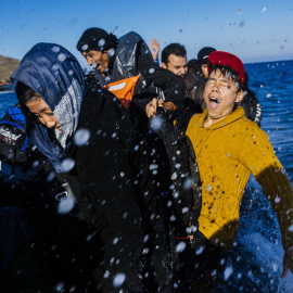 Refugiados y migrantes reaccionan al llegar en un bote a la isla griega de Lesbos, después de cruzar el mar Egeo desde Turquía, el 15 de octubre de 2015. AFP/DIMITAR DILKOFF