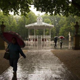 Paseantes se protegen de la lluvia en el parque de la Florida de Vitoria, País Vasco. / EFE