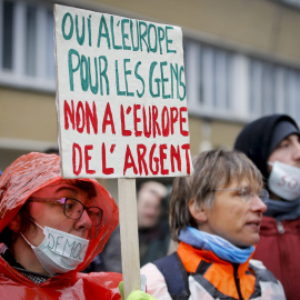 Una activista sostiene una pancarta en la que se puede leer "Sí a la Europa de las personas, no a la Europa del dinero" ante la sede de la UE, en Bruselas. EFE/Olivier Hoslet
