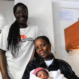 La madre posa junto a su bebé, Miracle, y la comadrona/ Guglielmo Mangiapane (SOS Méditerranée)