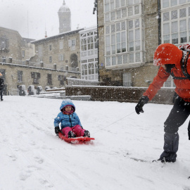 Un niño se desliza con un trineo en la Plaza de la Virgen Blanca, en Vitoria. /EFE