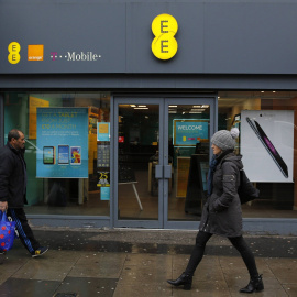 Unos peatones pasan por delante de una tienda de la operadora de telefonía móvil EE en Londres. REUTERS/Suzanne Plunkett