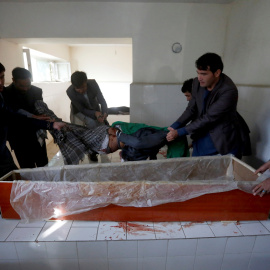 Varias personas levantan el cadáver de un civil muerto en un hospital de Kabul. - REUTERS