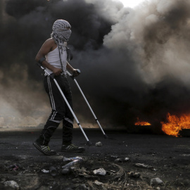 Un manifestante palestino camina con muletas durante los enfrentamientos con las tropas israelíes cerca del asentamiento judío de Bet El, cerca de la ciudad cisjordana de Ramala. REUTERS / Ammar Awad