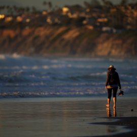 Una mujer pasea en una playa de Cardiff (California). REUTERS/Mike Blake