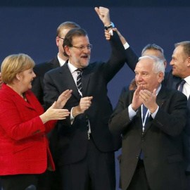 El presidente del Consejo Europeo, Donald Tusk (d), levanta el brazo del presidente del Gobierno, Mariano Rajoy (c), junto al presidente el PPE, Joseph Daul (2d), y la canciller alemana, Angela Merkel (2i), mientras posan para la foto de fa