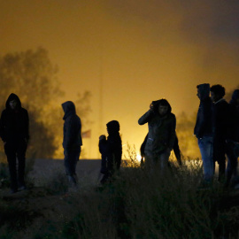 Varias inmigrantes en La Jungla de Calais, con gases lacrimógenos a sus espaldas. REUTERS/Pascal Rossignol