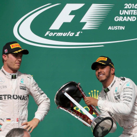 Lewis Hamilton levanta el trofeo de ganador del GP de EEUU ante la mirada de Rosberg. /REUTERS