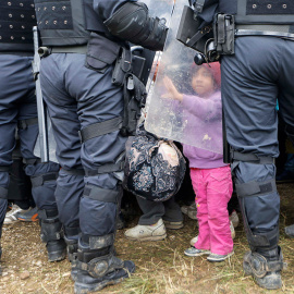 Una pequeña toca el escudo de un policía antidisturbios tras cruzar la frontera de Croacia, en Rigonce, Eslovenia.- SRDJAN ZIVULOVIC (REUTERS)