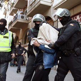 Uno de los tres detenidos por la Guardia Civil, implicados en una red de captación y envío de personas para su incorporación a la organización terrorista DAESH, sale custodiado por agentes de la benemérita en la calle Marina de Barcelona. E