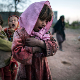 Una niña mira a sus amigos, mientras juegan a la rayuela a las afueras de Islamabad (Pakistán). /ZOHRA BENSEMRA (REUTERS)