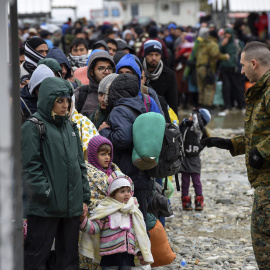 Un agente de policía macedonio conversa con un grupo de refugiados antes de que éstos puedan subir a un tren que se dirige hacia a la frontera serbia, cerca de la ciudad de Gevgelija, Macedonia. EFE