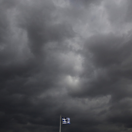 La bandera griega ondea sobre la Acrópolis de Atenas, bajo un cielo cubierto de nubes de tormenta. REUTERS/Yannis Behrakis