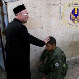 Sacerdote bendice a un miliciano del Consejo Militar Siriaco de Siria.