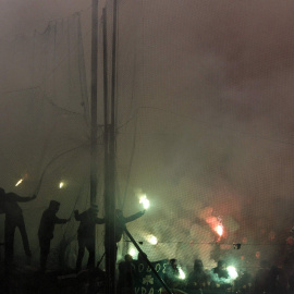 Aficionados del Panathinaikos lanzan bengalas durante el derbi. REUTERS/Kostas Tsironis