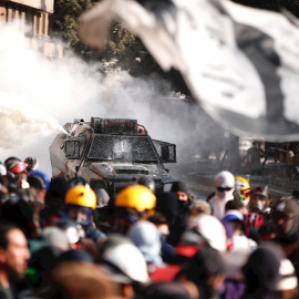Manifestantes se enfrentan con las Fuerzas Especiales de Carabineros mientras una bandera con la cara del cantautor chileno Víctor Jara, asesinado durante la dictadura militar, ondea este viernes en los alrededores de la plaza Italia de San