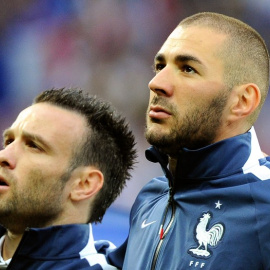 Benzema y Valbuena escuchan junto el himno francés en un partido de su selección. /AFP