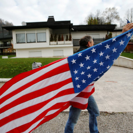 Un hombre ondea una bandera de Estados Unidos delante de la casa de los padres de Melania Trump. / SRDJAN ZIVULOVIC