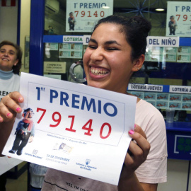 Una joven sostiene el décimo premiado en la Lotería de Navidad de 2015. / EFE