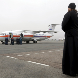 An Orthodox priest looks at a Russian emergencies ministry's plane, carrying the remains of victims of the plane crash in Egypt, shortly after its landing on the airfield of Pulkovo airport outside St. Petersburg, Russia, November 6, 2015. 