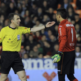 El árbitro David Fernández Borbalán ante el portero Diego Alves en un partido de Liga en 2014. /AFP