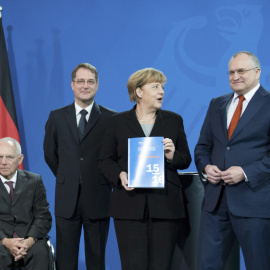 La canciller alemana Angela Merkel con el informe anual del Consejo Asesor de Economistas del Gobierno alemán, con su presidente Christoph Schmid a su izquierda. REUTERS/Stefanie Loos