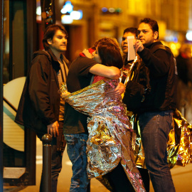 Supervivientes se abrazan antes de ser evacuados en autobús, cerca de la sala de conciertos Bataclan en París, donde los terroristas han matado a más de 100 rehenes.-  AFP PHOTO / FRANCOIS GUILLOT