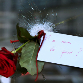 Una rosa colocada en un agujero de bala en una ventana del restaurante atacado, el día después de los atentados en París. "En nombre de qué?" , dice la nota.- REUTERS / Pascal Rossignol