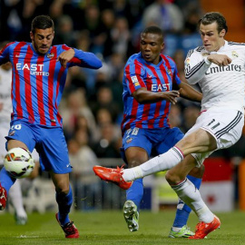 El centrocampista galés del Real Madrid Gareth Bale (d) dispara ante los jugadores del Levante Víctor Camarsa (i) y el mozambiqueño Simao, durante el partido de Liga en Primera División disputado esta noche en el estadio Santiago Bernabéu, 