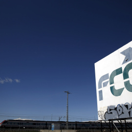 Un tren pasa cerca de un cartel de la empresa de construcción y servicios  FCC, cerca de la localidad madrileña de Tres Cantos. REUTERS/Susana Vera