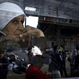 Una anciana mira por la ventana de un autobús que traslada a refugiados sirios e iraquíes a las nuevas instalaciones de acogida en el puerto de Skaramangas. EFE