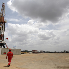 FILE PHOTO: An oilfield worker walks next to drilling rigs at an oil well operated by Venezuela's state oil company PDVSA, in the oil rich Orinoco belt, near Morichal at the state of Monagas April 16, 2015. REUTERS/Carlos Garcia Rawlins/Fil