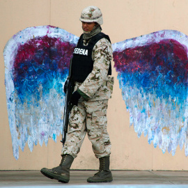Un soldado camina ante un graffiti que representa las alas de un ángel, realizado por el artista Colette Miller, en Ciudad Juárez (México). /JOSÉ LUIS GONZÁLEZ (REUTERS)