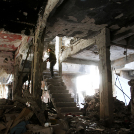 Un combatiente toma posición en las escaleras de un edificio destrozado por los bombardeos en Yarmuk. - YOUSSEF KARWASHAN / AFP