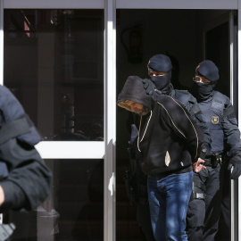 Agentes de los Mossos d'Esquadra custodian a una de las nueve personas que han sido detenidas en el marco de una operación contra el terrorismo yihadista que están llevando a cabo la policía catalana, coordinada por el juzgado número 1 de l