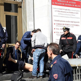 Policías y miembros de los servicios de rescate asisten a un herido a las puertas del Palacio de Justicia en Milán. / EFE