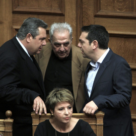 El primer ministro de Grecia Alexis Tsipras, habla con el ministro de Defensa y socio de Gobierno, Panos Kammenos, y con el ministro de estado Alekos Flabouraris, a su llegada a la sesión del Parlamento. EFE/SIMELA PANTZARTZI