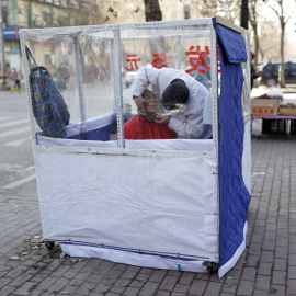 Un barbero afeita a un cliente en una pequeña tienda situada en la acera. Provincia de Liaoning, China. REUTERS/Sheng Li