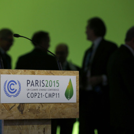 Varios participantes en la cumbre del clima dialogan tras el atril. REUTERS/Stephane Mahe