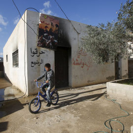 Niño palestino monta su bicicleta delante de la casa de la familia Dawabshe cerca de Nablús. REUTERS/Abed Omar Qusini