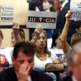 Los familiares de las víctimas de un accidente de tren en 2012 sostienen carteles que ponen "Justicia", sentados detrás de los acusados en una sala de audiencias en Buenos Aires, Argentina , 29 de diciembre de 2015. 51 personas murieron en 