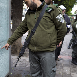 Un agente de policía de fronteras israelía señala uno de los agujeros de bala producido por los disparos de un árabe-israelí que mató el viernes a dos personas e hirió a siete en un pub de Tel Aviv. EFE/EPA/JIM HOLLANDER